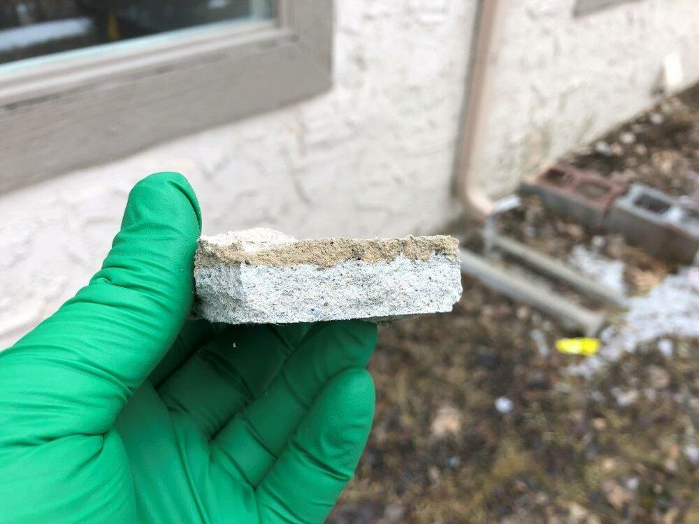 Gloved hand carefully collecting an asbestos material sample